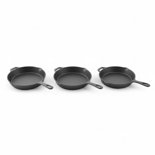 Three classic uncoated cast iron skillets neatly arranged on white background